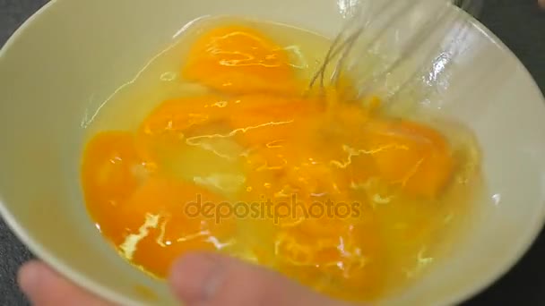 Manualy whisking de ovos crus em taça de vidro em câmera lenta, Whipping eggs with a metal whisk, misturando ovos com batedor manual — Vídeo de Stock