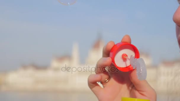 Mooi meisje blaast bellen. Aantrekkelijke jonge vrouw blazen in het Budapest bubble — Stockvideo