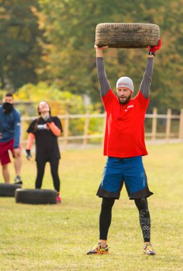 Bir adam bir lastik başının üzerinde tutar..