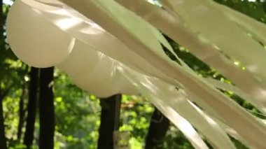 Ormandaki düğün süsleri, beyaz balonlar ve rüzgarda savrulan beyaz kumaş şeritleri. Tam HD, ses yok.