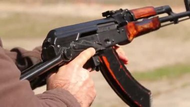 Ukrayna, Kyiv - 6 Nisan 2016. Kask giymiş Ukrayna armalı bir adam, kalaşnikofun içine bir şarjör yerleştirir, panjuru yerleştirir, nişan alır ve ateş eder. Yakın plan, Hd, ses yok.