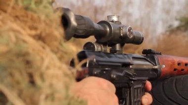 Kamuflajlı keskin nişancı kıyafeti giymiş bir nişancı, keskin nişancı tüfeği optik görüş, tüfeği yakın plan, full HD, ses olmadan hedef alır..
