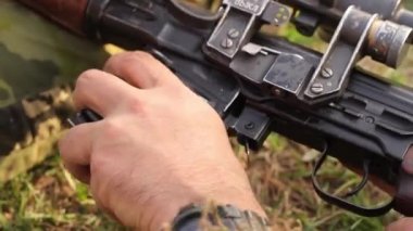 Bir erkek eli, optik görüşü olan keskin nişancı tüfeğine cephaneli bir şarjör yerleştiriyor. Rus yapımı bir tüfek ve optik. Tam HD.