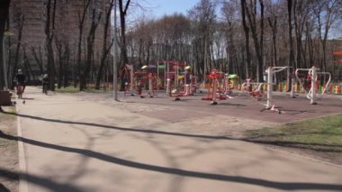 Ukrayna, Kyiv - 4 Nisan 2020. Baba ve oğul, Ukrayna hükümeti tarafından ilan edilen karantina sırasında, solunum yolu için maskeli bisikletlerle parkta bir ara sokağa biniyorlar..