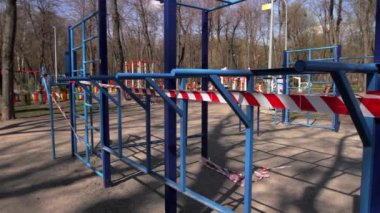 Ukrayna, Kyiv - 4 Nisan 2020. Açık hava spor sahası sinyal kasetleriyle kapalıdır. Arka planda insanlar cadde boyunca yürür. Kamerayı sağdan sola çevir. Karantina, COVID 19