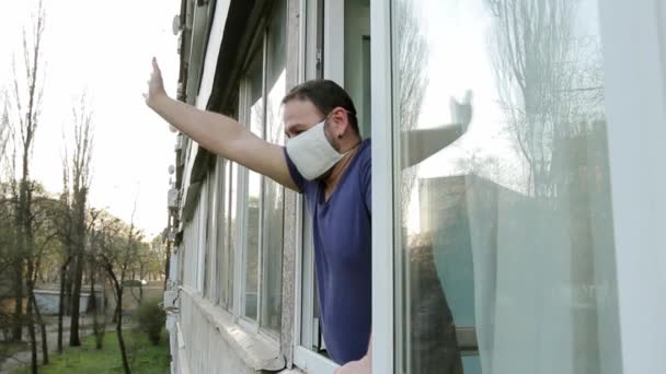 Een Man Met Een Medisch Masker Opent Een Raam Zwaaiend — Stockvideo