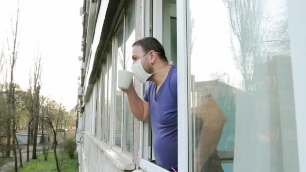 Een Man Met Een Medisch Masker Bij Het Raam Probeert — Stockvideo