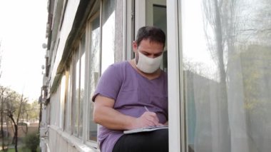 Sokaktan gelen statik kamera. Tıbbi maskeli bir adam pencere kenarına oturur ve bir defterde kalemle yazar, sonra hoşnutsuz bir şekilde defterden bir çarşaf yırtıp, kenara atar ve bırakır.. 