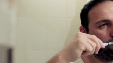 Uykulu orta yaşlı bir adam banyoda diş macunu olmadan dişlerini fırçalıyor. Kamerayı soldan sağa doğru hareket ettiriyor, yüzünü tamamen kapatıyor. Tam HD, ses yok.