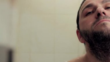 Banyoda uyuyan orta yaşlı bir adam tıraş köpüğü kullanmadan tıraş oluyor. Kamera hareketi soldan sağa, tam yüz yakın çekim. Tam HD, ses yok.