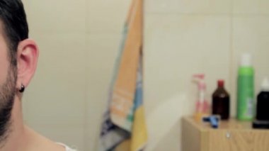 Uykulu orta yaşlı bir adam banyoda burun kıllarını budayarak tıraş ediyor. Kamera sağa sola hareket ediyor, tam yüz. Tam HD, ses yok.