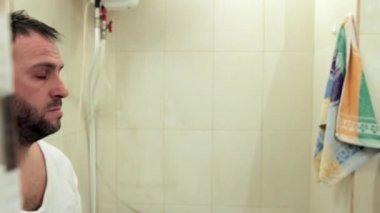 Uykulu bir adam banyoya girer, gözlerini ovuşturur ve iç çeker, aynada kendine bakar. Profilde, yakın plan, kameranın soldan sağa hareketi, tam otomatik, ses yok.