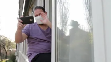 Yüzünde tıbbi maske olan bir adam pencere çerçevesine oturur, akıllı bir telefonla görüntülü sohbet yoluyla iletişim kurar, veda öpücüğü verir ve gider. Kameralar sokaktan daireye hareket ediyor