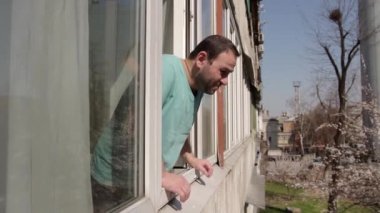 Açık pencerenin yanındaki adam derin bir nefes alır ve hapşırmaya ve öksürmeye başlar, çıkar ve pencereyi kapatır. Pencere çerçevesinde sağdan sola hareket eden bir kamera var. orta boy, Full HD