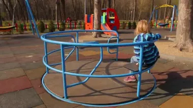 Bir kız atlıkarıncaya biniyor, arka planda çocuksuz bir oyun alanı görünüyor.