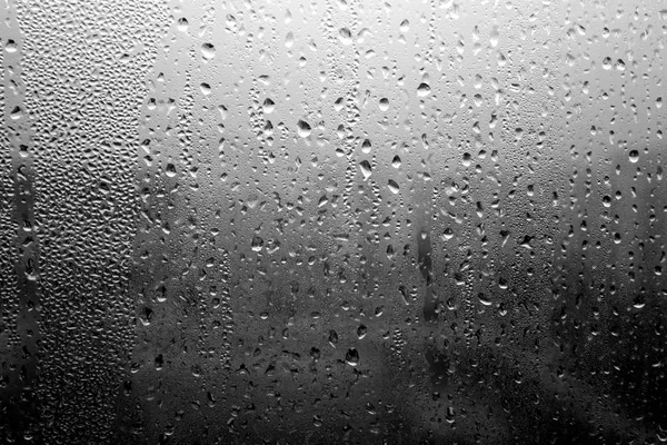 Капли дождя на окне крупным планом черно-белыми — стоковое фото