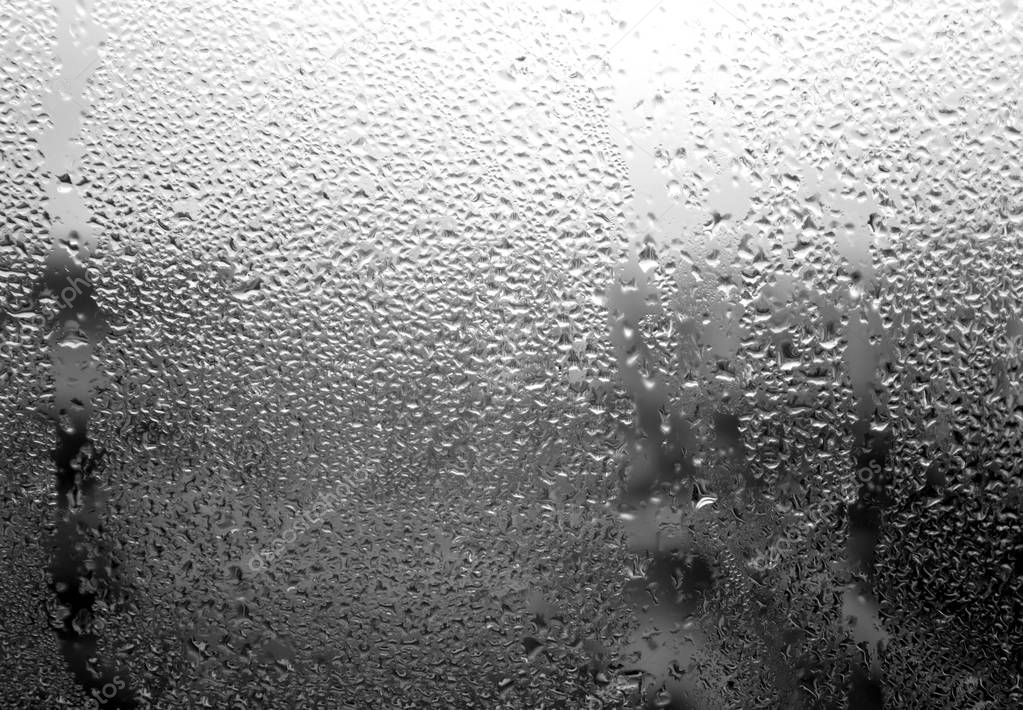 Raindrops on window close-up in black and white. 