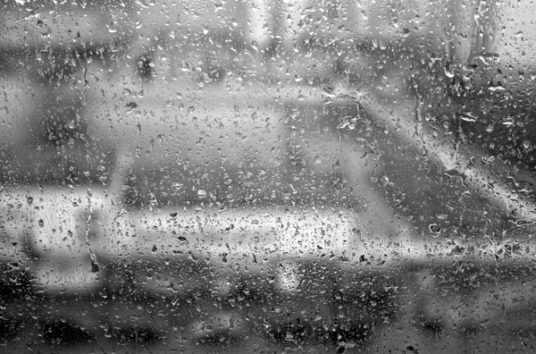 Chuva cai na janela com efeito borrão em preto e branco . — Fotografia de Stock