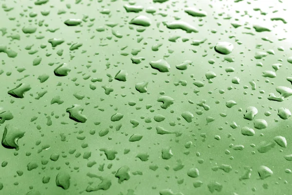 Regentropfen auf grüner Metalloberfläche mit Unschärfeeffekt — Stockfoto