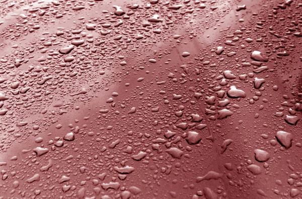 Σταγόνες βροχής σε κόκκινη μεταλλική επιφάνεια. — Φωτογραφία Αρχείου
