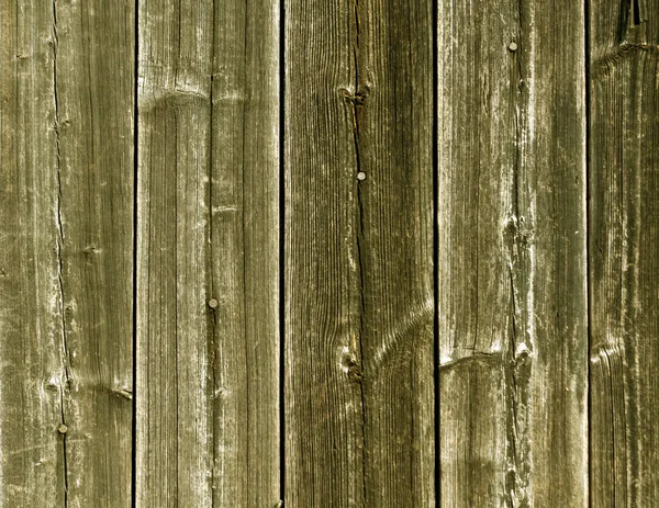 Weathered yellow wooden fence texture with nails.