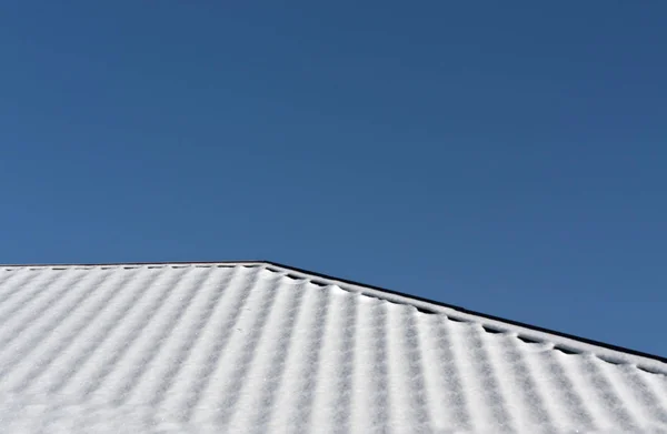 Hausdach im Schnee vor blauem Himmel. — Stockfoto