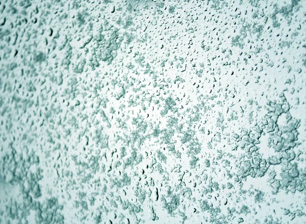Neige et gouttes sur verre de voiture tonique cyan avec effet flou . — Photo