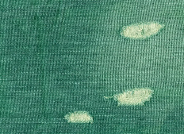 Torn green jeans texture.
