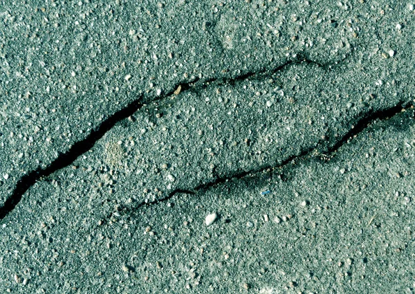 Damaged cyan toned asphalt surface.