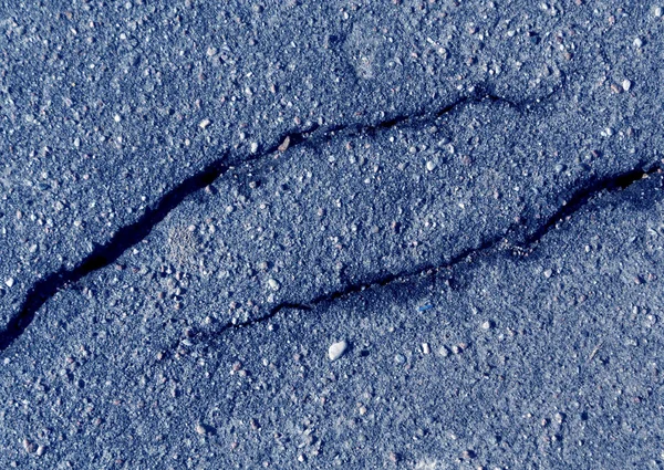 Damaged blue toned asphalt surface.