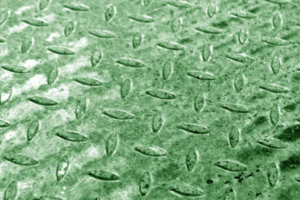Close-up of green metal floor pattern with blur effect.