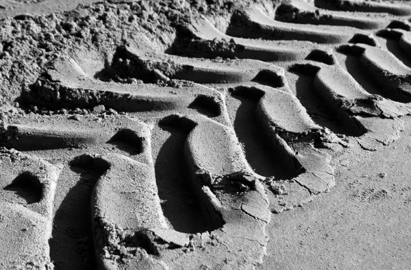 Faixas de pneus na areia com efeito borrão em preto e branco . — Fotografia de Stock
