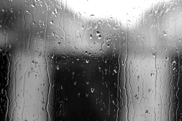 Gotas de lluvia en la ventana con efecto difuminado en blanco y negro —  Fotos de Stock