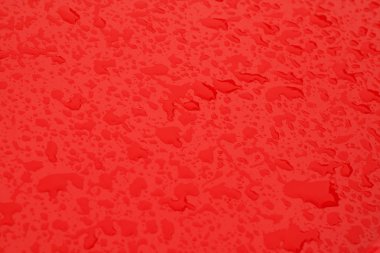 Kırmızı renkli metal yüzeyinde su damlaları.