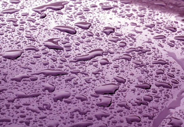 Gotas de agua en la superficie de metal de color púrpura con efecto difuminado — Foto de Stock