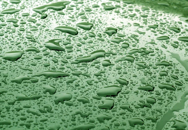 Bulanıklaştırma efekti ile yeşil renk metal yüzeyinde su damlaları — Stok fotoğraf