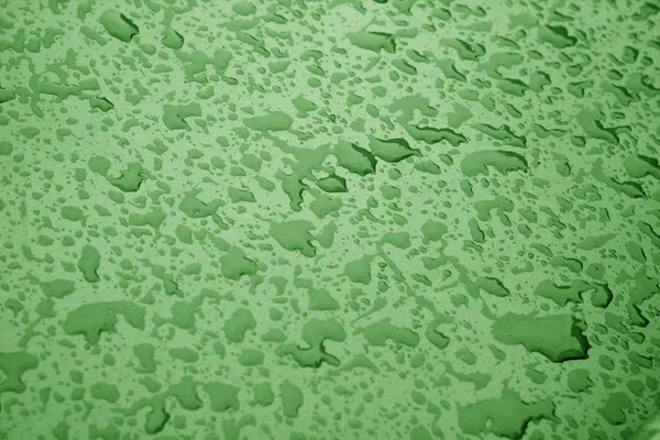 Yeşil renkli metal yüzeyinde su damlaları.