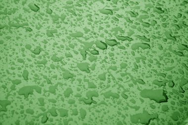 Yeşil renkli metal yüzeyinde su damlaları.