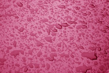 Pembe renkli metal yüzeyinde su damlaları.