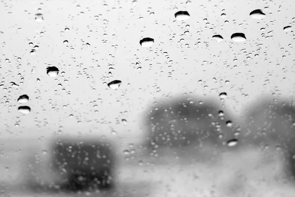 Vista de inverno através da janela com foco em gotas de chuva em preto e — Fotografia de Stock