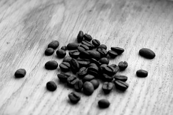 Grãos de café na placa de madeira com efeito borrão em preto e branco — Fotografia de Stock