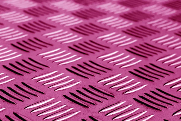 Diamond shaped metal floor pattern with blur in pink tone.