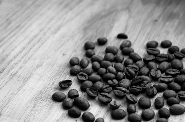 Grãos de café na placa de madeira com efeito borrão em preto e branco — Fotografia de Stock