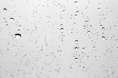 Araba penceresinde siyah beyaz yağmur damlaları.