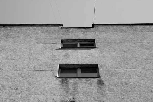 Windows and cement wall of old house in black and white.