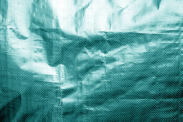 Metalized plastic wrap texture with crumples in cyan tone.