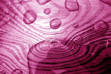 Su, ahşap yüzeye pembe tonda düşer..