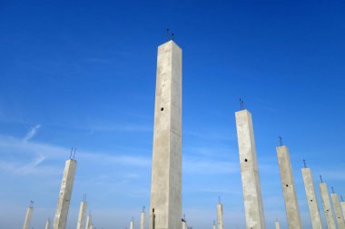 Mavi gökyüzüne karşı beton inşaat direkleri