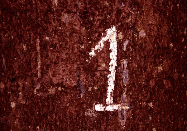 Mão escrita número um na parede grungy cor vermelha — Fotografia de Stock
