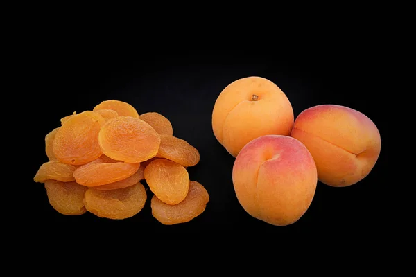 Meruňky žluté barvy a sušené meruňky na černé poza — Stock fotografie